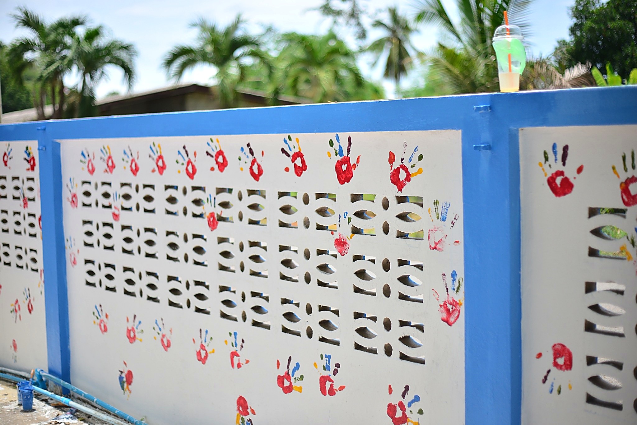 A decorative Hand to Hand compound wall covered in colorful children's handprints