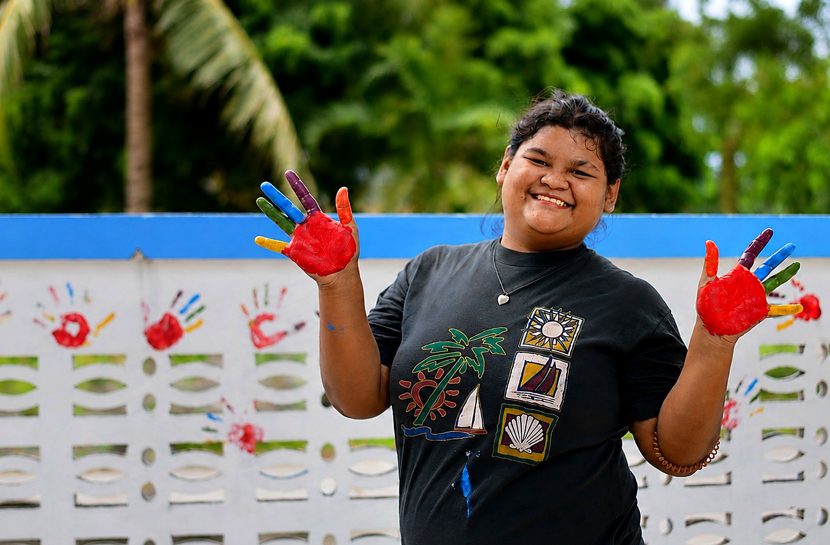 A young woman from Hand to Hand's programs smiling with painted hands