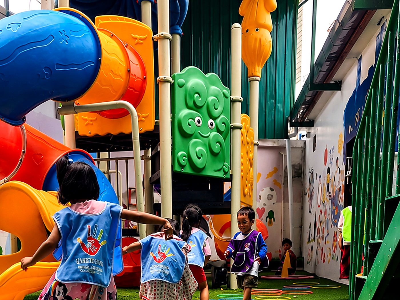 Hand to Hand Kids Club children in matching bibs playing an obstacle course game on the playground