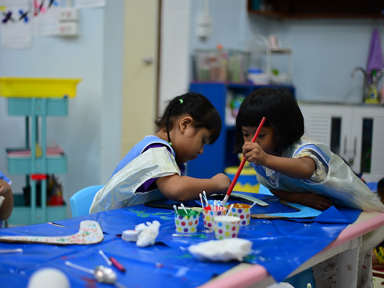 Two Hand to Hand pre-school children painting together at a craft table