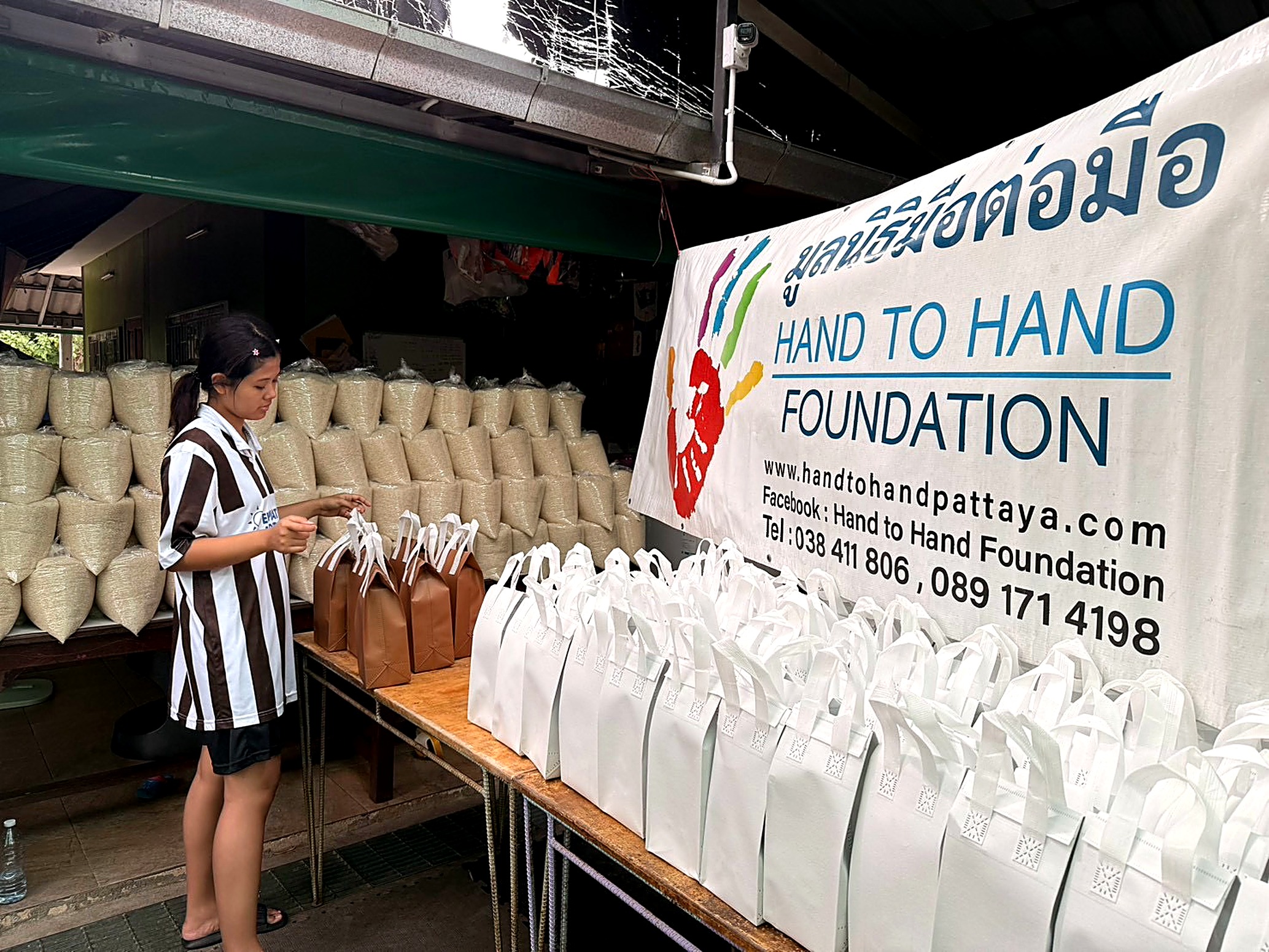 A Hand to Hand volunteer preparing care packages of rice and food bags for distribution